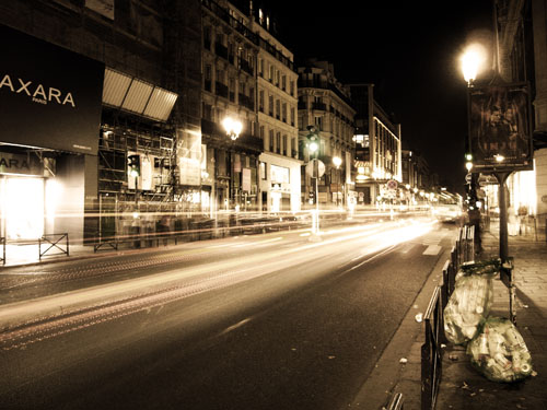 Traffic at night in Paris and some garbage on the sidewalk.